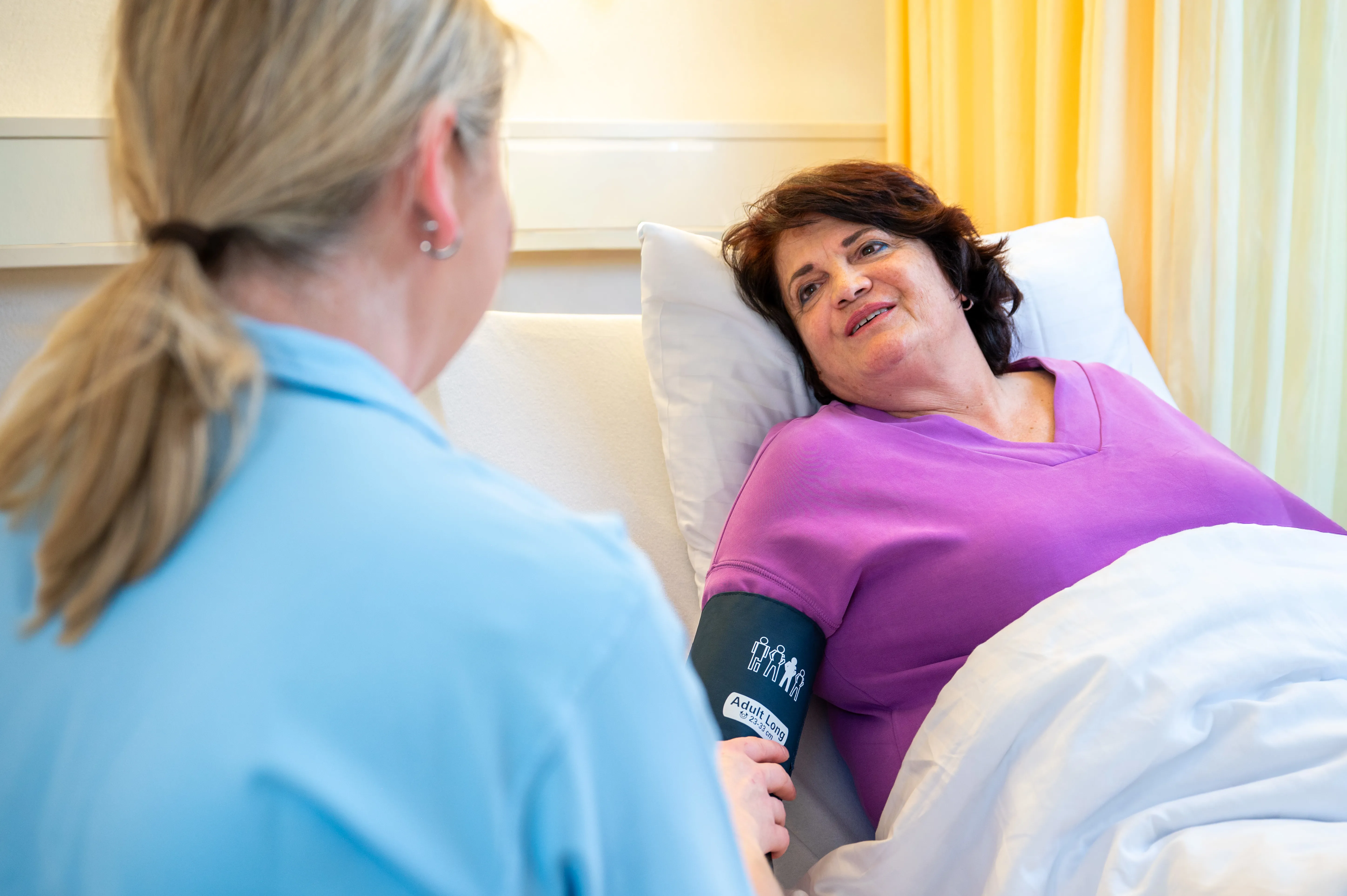 Pflegefachperson misst den Blutdruck einer Patientin