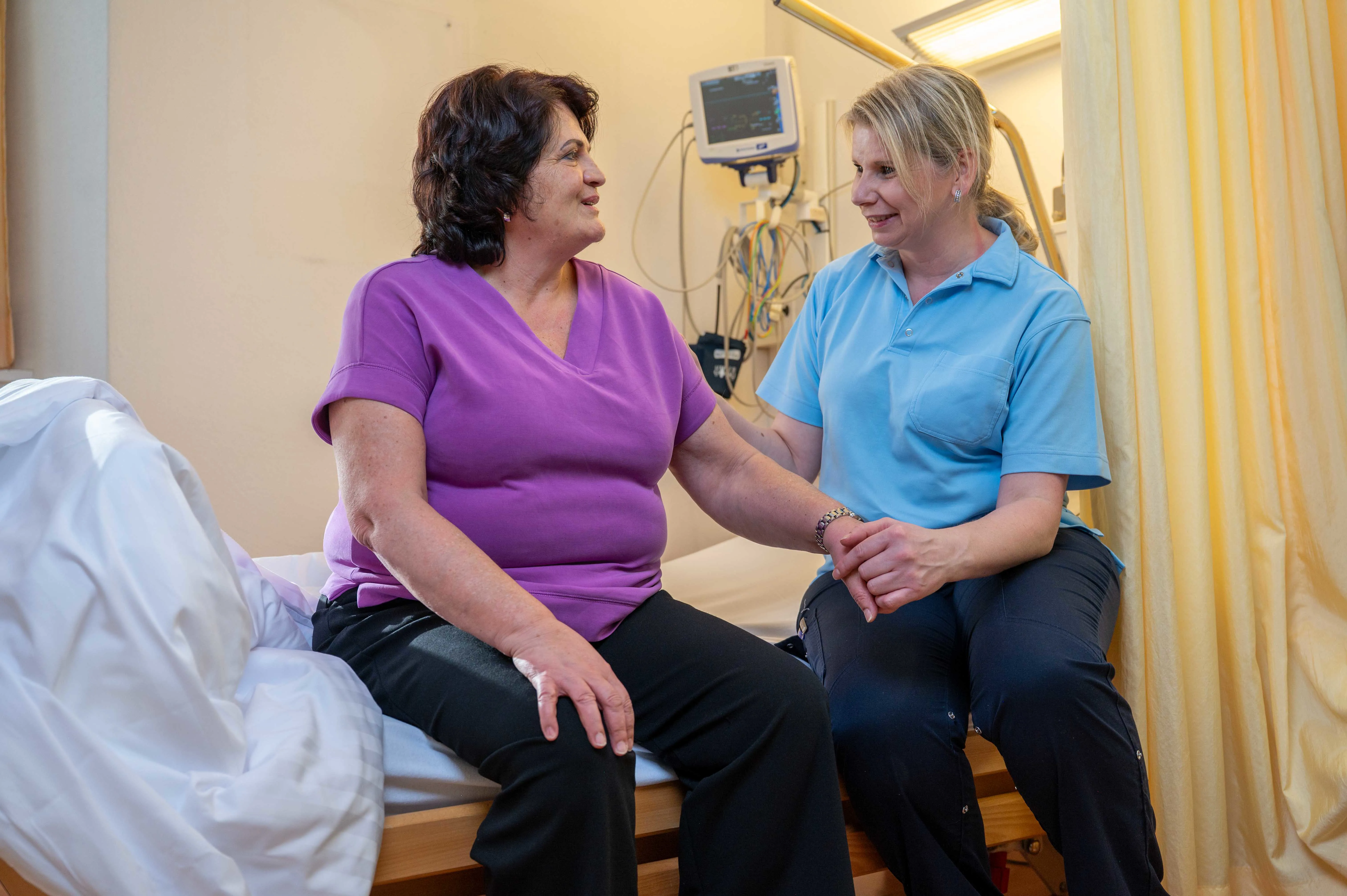Pflegefachperson begleitet eine Patientin während ihres Aufenthalts